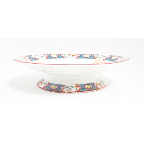 199 - A Minton style footed comport / tazza with chinoiserie decoration depicting three figures on a terra... 