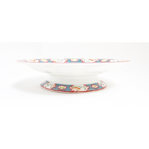 199 - A Minton style footed comport / tazza with chinoiserie decoration depicting three figures on a terra... 