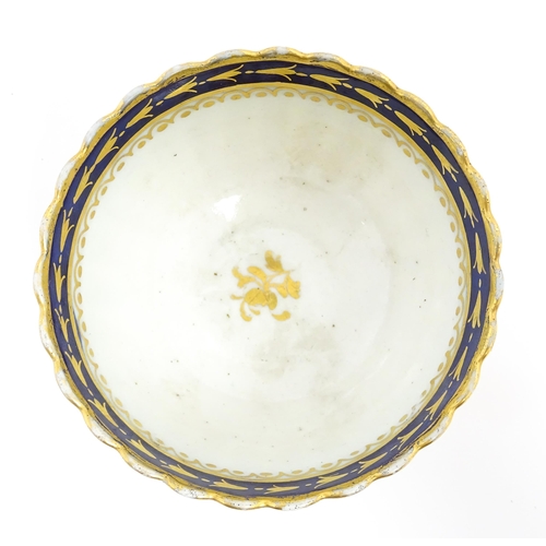 204 - An English tea bowl with lobed detail, banded gilt borders and gilt foliate motif to centre. Marked ... 