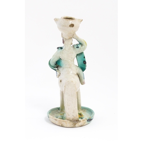 212 - A Continental faience style candlestick modelled as a figure on horseback carrying a vessel on his h... 