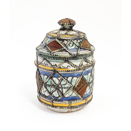 213 - A Persian pot and cover with banded decoration and applied geometric detail. Approx. 6 1/2