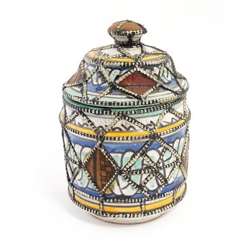 213 - A Persian pot and cover with banded decoration and applied geometric detail. Approx. 6 1/2