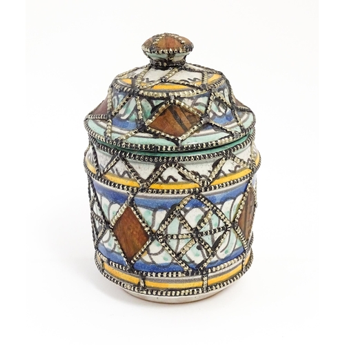 213 - A Persian pot and cover with banded decoration and applied geometric detail. Approx. 6 1/2