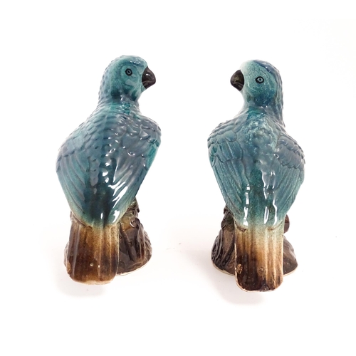 216 - A pair of ceramic models of parrots perched on a branch. Approx. 7 3/4