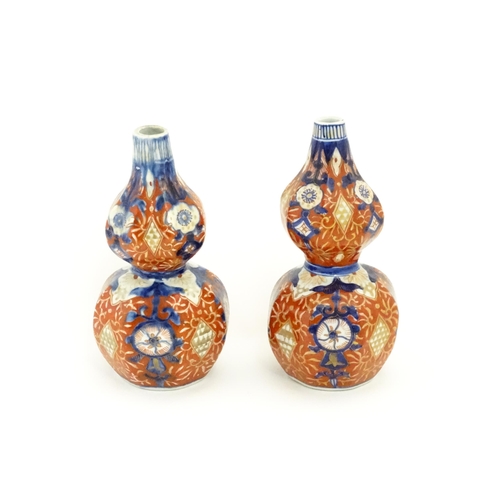 10 - A matched pair of Japanese double gourd vases decorated in the Imari palette with floral motifs and ... 