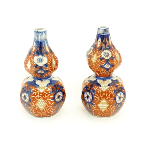 10 - A matched pair of Japanese double gourd vases decorated in the Imari palette with floral motifs and ... 