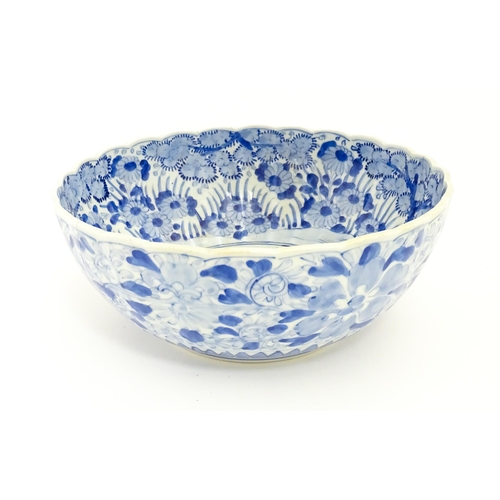 21 - A Japanese blue and white bowl with scalloped edge decorated with a central vase of flowers bordered... 