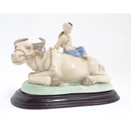 32 - A Chinese model of a young boy riding a water buffalo. Approx. 7 1/4