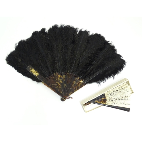 1119 - An early 20thC black feather fan with 20 faux tortoiseshell sticks. Together with another smaller ex... 