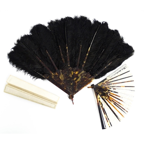 1119 - An early 20thC black feather fan with 20 faux tortoiseshell sticks. Together with another smaller ex... 