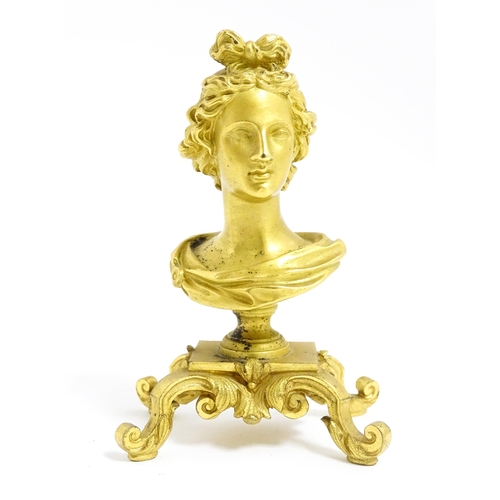 1031 - A small 19thC gilt bronze bust of a lady with a ribbon in her hair, on a scrolled gilt base. Approx.... 