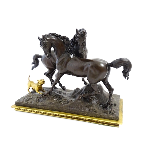 1037 - A 20thC cast bronze sculpture depicting two horses with a gilt dog barking at them, on a naturalisti... 