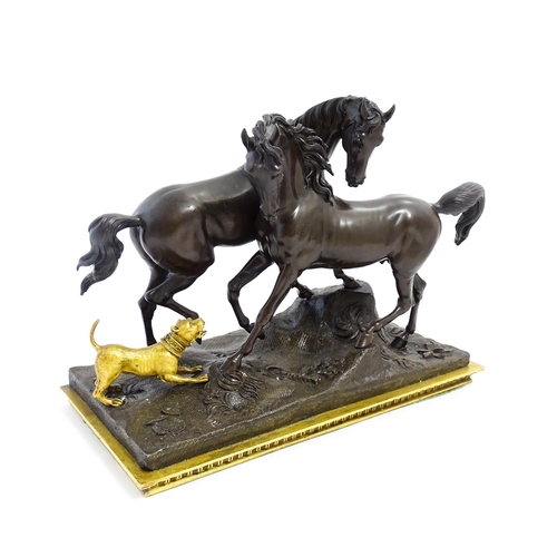 1037 - A 20thC cast bronze sculpture depicting two horses with a gilt dog barking at them, on a naturalisti... 