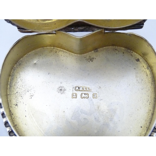 525 - A silver pot of heart form with embossed decoration and hinged lid opening to reveal a gilded interi... 