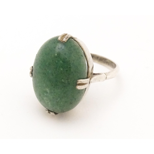 572 - An Art Deco white metal ring set with green stone cabochon. Ring size approx. N.