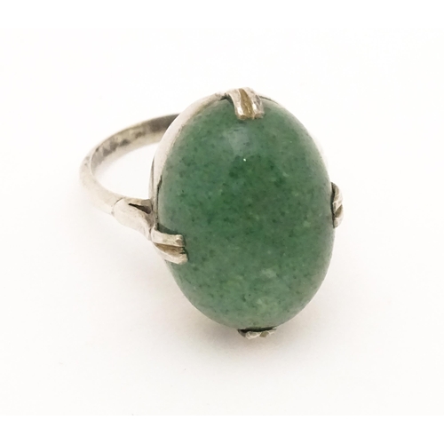 572 - An Art Deco white metal ring set with green stone cabochon. Ring size approx. N.