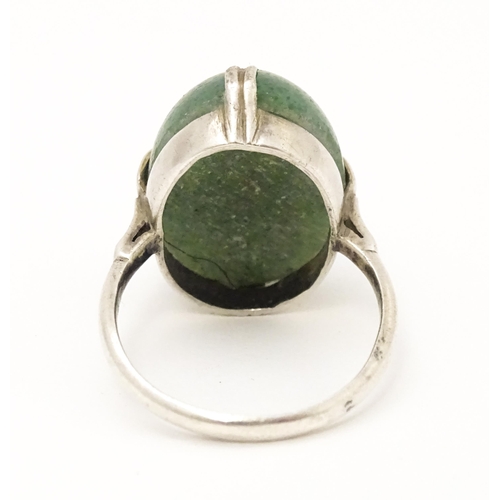 572 - An Art Deco white metal ring set with green stone cabochon. Ring size approx. N.