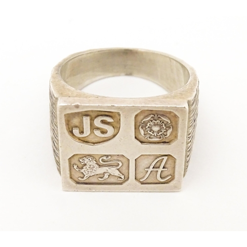 616 - A silver signet ring with hallmark decoration to top. Hallmarked Sheffield 1975 maker Jack Spencer (... 