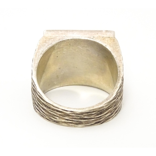 616 - A silver signet ring with hallmark decoration to top. Hallmarked Sheffield 1975 maker Jack Spencer (... 