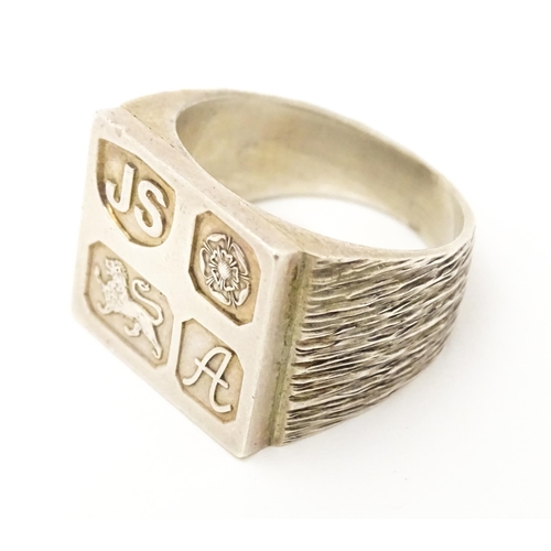 616 - A silver signet ring with hallmark decoration to top. Hallmarked Sheffield 1975 maker Jack Spencer (... 