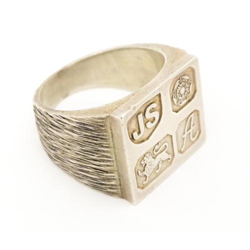 616 - A silver signet ring with hallmark decoration to top. Hallmarked Sheffield 1975 maker Jack Spencer (... 