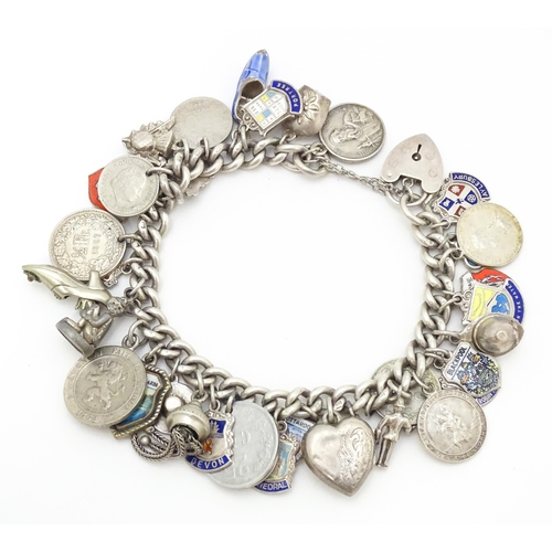 758 - A silver charm bracelet with various silver and silver plate charms, some coin formed.