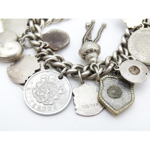 758 - A silver charm bracelet with various silver and silver plate charms, some coin formed.