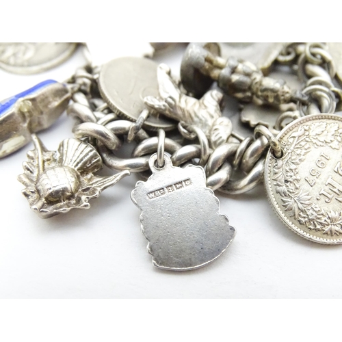 758 - A silver charm bracelet with various silver and silver plate charms, some coin formed.