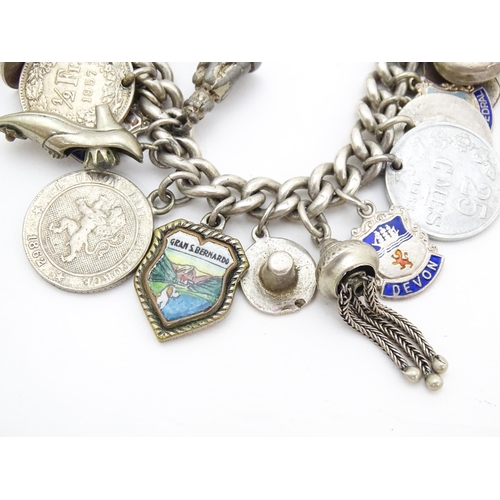 758 - A silver charm bracelet with various silver and silver plate charms, some coin formed.