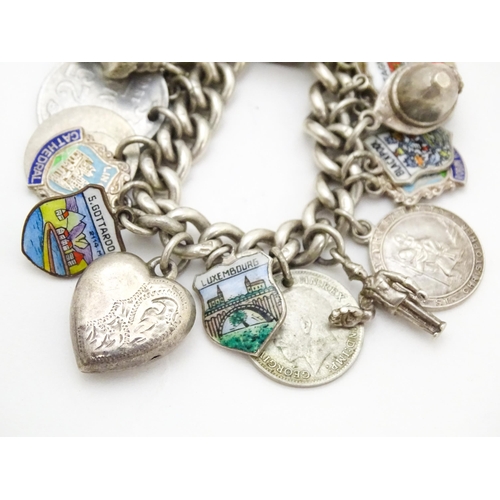 758 - A silver charm bracelet with various silver and silver plate charms, some coin formed.