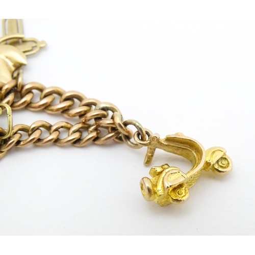 764 - A 9ct gold twin chain charm bracelet set with various 9ct gold and yellow metal charms to include a ... 