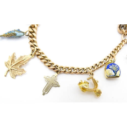 764 - A 9ct gold twin chain charm bracelet set with various 9ct gold and yellow metal charms to include a ... 