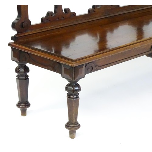 1439 - A Victorian mahogany bench, with a shaped top rail, carved terminals and an armorial shield to the c... 