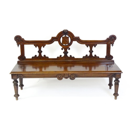 1439 - A Victorian mahogany bench, with a shaped top rail, carved terminals and an armorial shield to the c... 