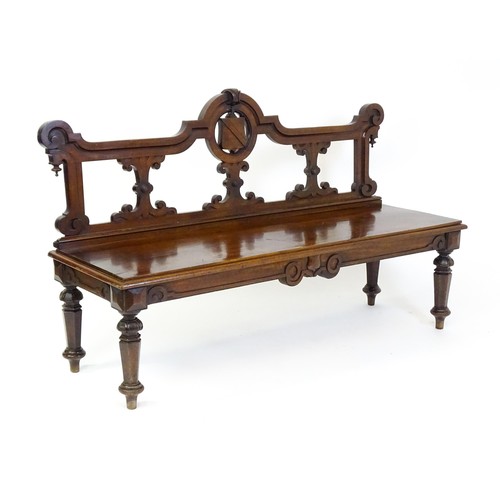 1439 - A Victorian mahogany bench, with a shaped top rail, carved terminals and an armorial shield to the c... 