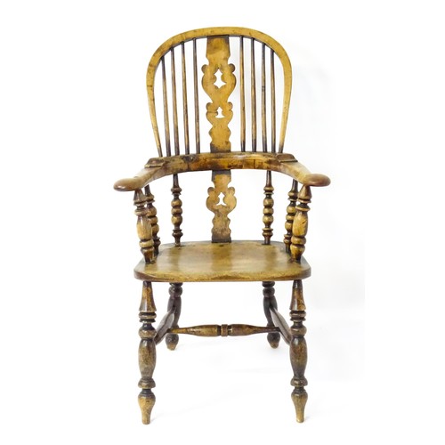 1453 - A mid 19thC Windsor chair with a double bow back, pierced back splat and swept arms above a shaped s... 