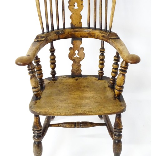 1453 - A mid 19thC Windsor chair with a double bow back, pierced back splat and swept arms above a shaped s... 