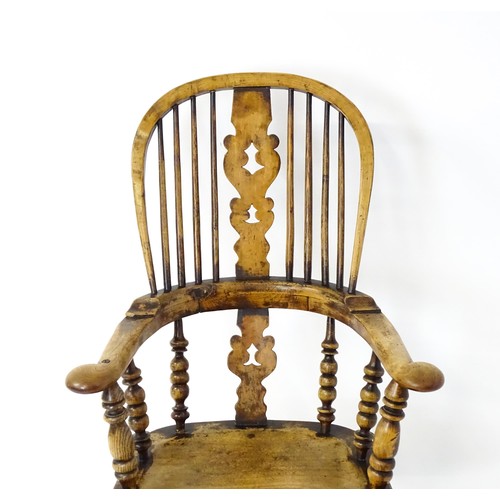 1453 - A mid 19thC Windsor chair with a double bow back, pierced back splat and swept arms above a shaped s... 