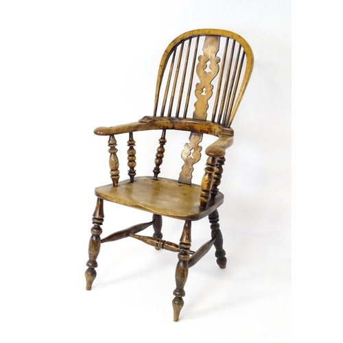 1453 - A mid 19thC Windsor chair with a double bow back, pierced back splat and swept arms above a shaped s... 