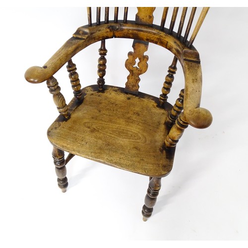 1453 - A mid 19thC Windsor chair with a double bow back, pierced back splat and swept arms above a shaped s... 