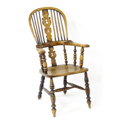 1453 - A mid 19thC Windsor chair with a double bow back, pierced back splat and swept arms above a shaped s... 