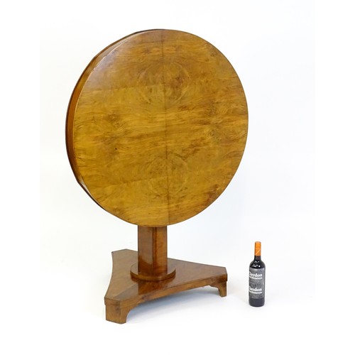 1472 - A 19thC walnut tilt top table of unusual proportions, with a circular table top above a canted pedes... 