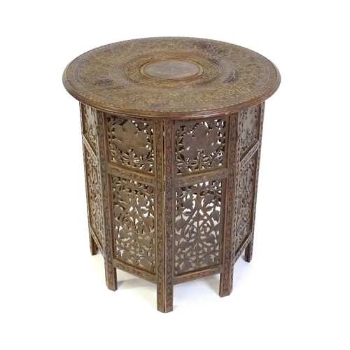 1474 - A late 19thC / early 20thC folding Islamic table with a floral carved top, brass inlay and the base ... 