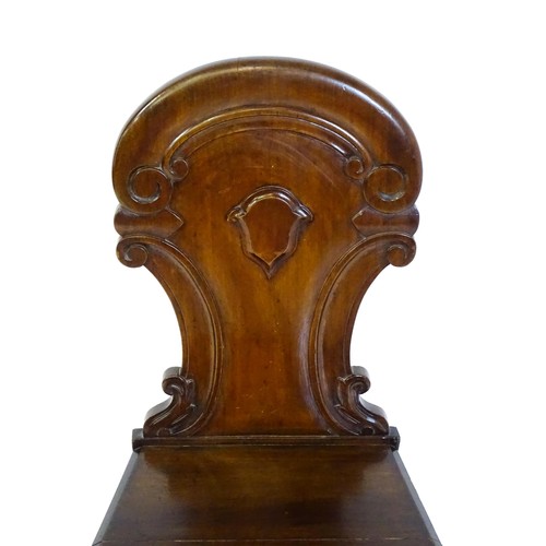 1497 - A Victorian mahogany hall chair with a carved backrest and raised on turned tapering front legs and ... 