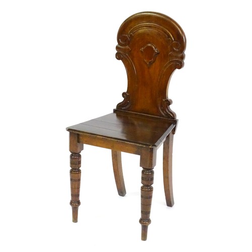 1497 - A Victorian mahogany hall chair with a carved backrest and raised on turned tapering front legs and ... 