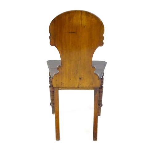 1497 - A Victorian mahogany hall chair with a carved backrest and raised on turned tapering front legs and ... 