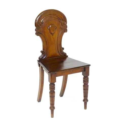 1497 - A Victorian mahogany hall chair with a carved backrest and raised on turned tapering front legs and ... 