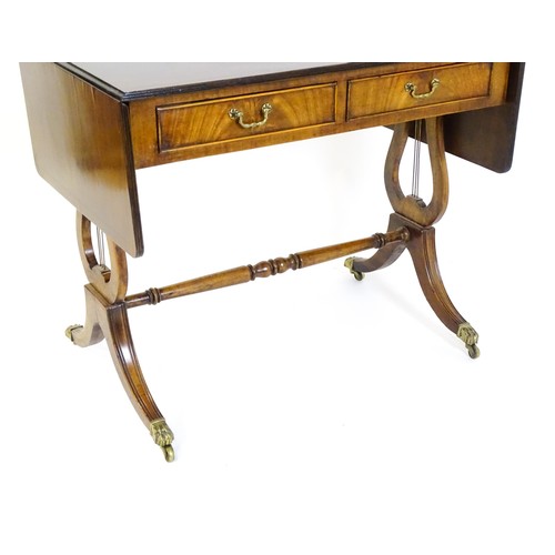 1512 - An early / mid 20thC  Regency style mahogany sofa table with drop leaves to either side, two frieze ... 