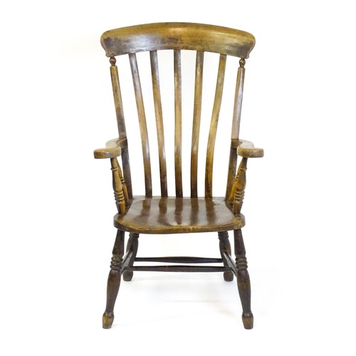 1516 - A late 19thC / early 20thC lathe back Windsor armchair, with swept arms, a shaped seat and raised on... 