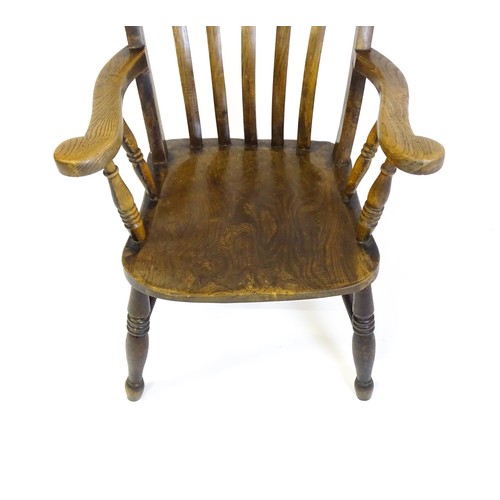 1516 - A late 19thC / early 20thC lathe back Windsor armchair, with swept arms, a shaped seat and raised on... 